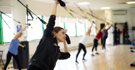 People exercising with suspension trainers in a fitness class.