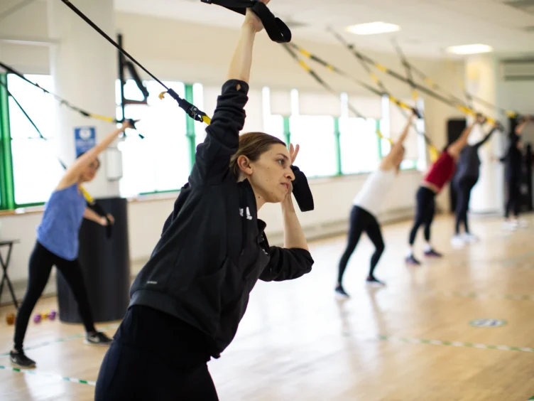 People exercising with suspension trainers in a fitness class.