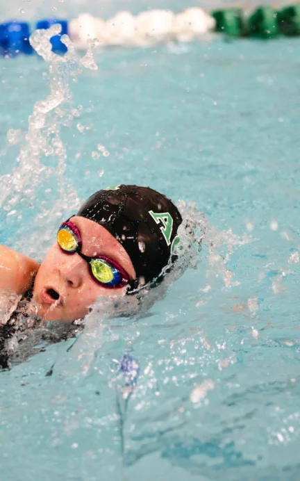 Swimmer in goggles and cap performing a freestyle stroke in a pool with lane dividers.